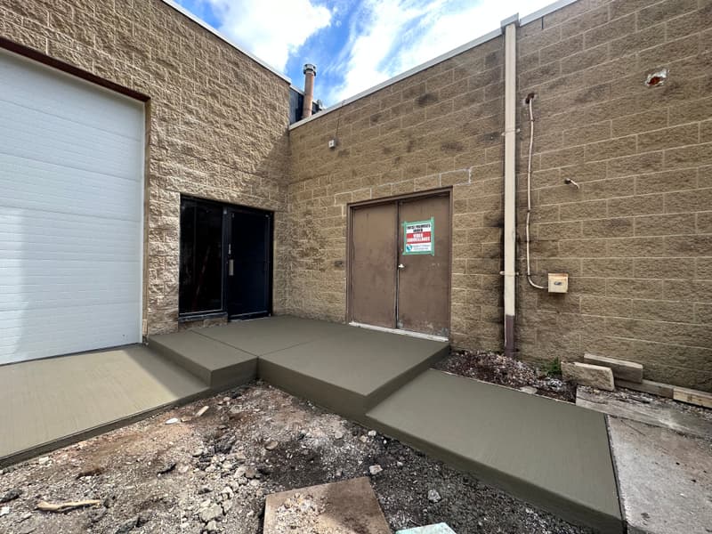 New concrete stoop and pad at a block commercial building entrance
