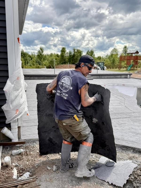 Crew member pressing a stamp mat into fresh concrete