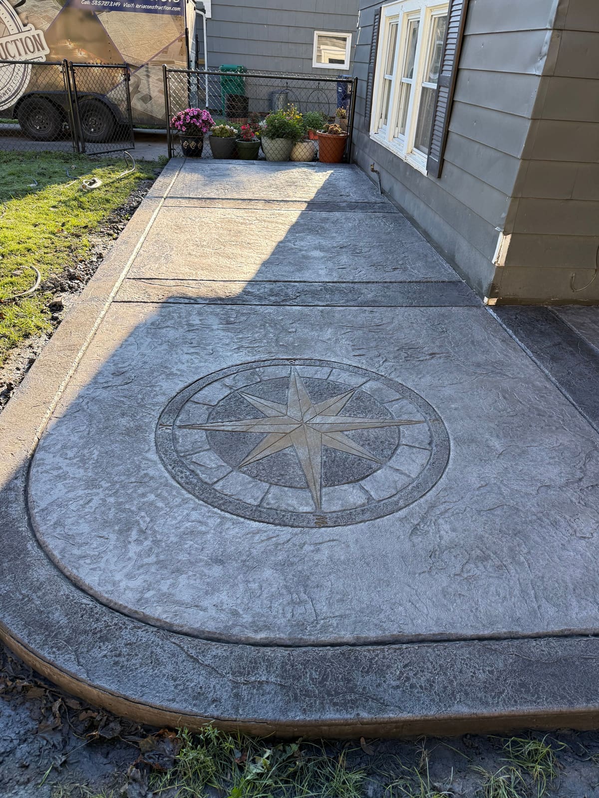 Stamped concrete patio with a custom compass-rose medallion and a curved border
