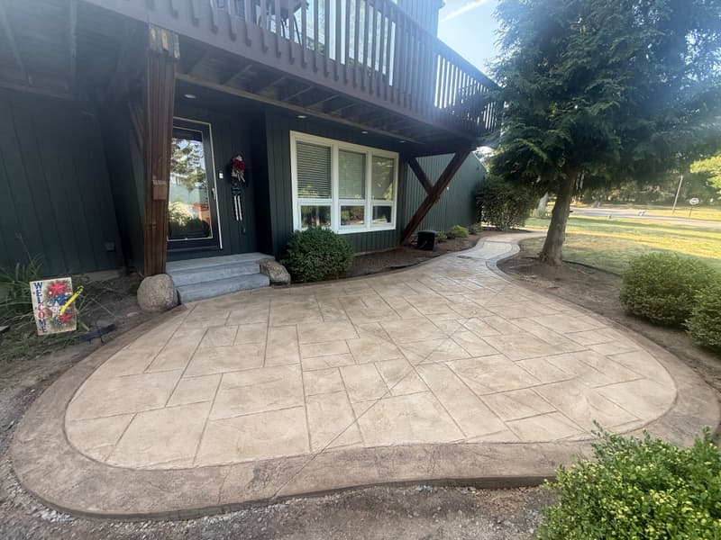 Curved tan stamped concrete patio with a darker border