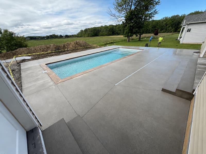 Wide concrete pool deck around a rectangular pool